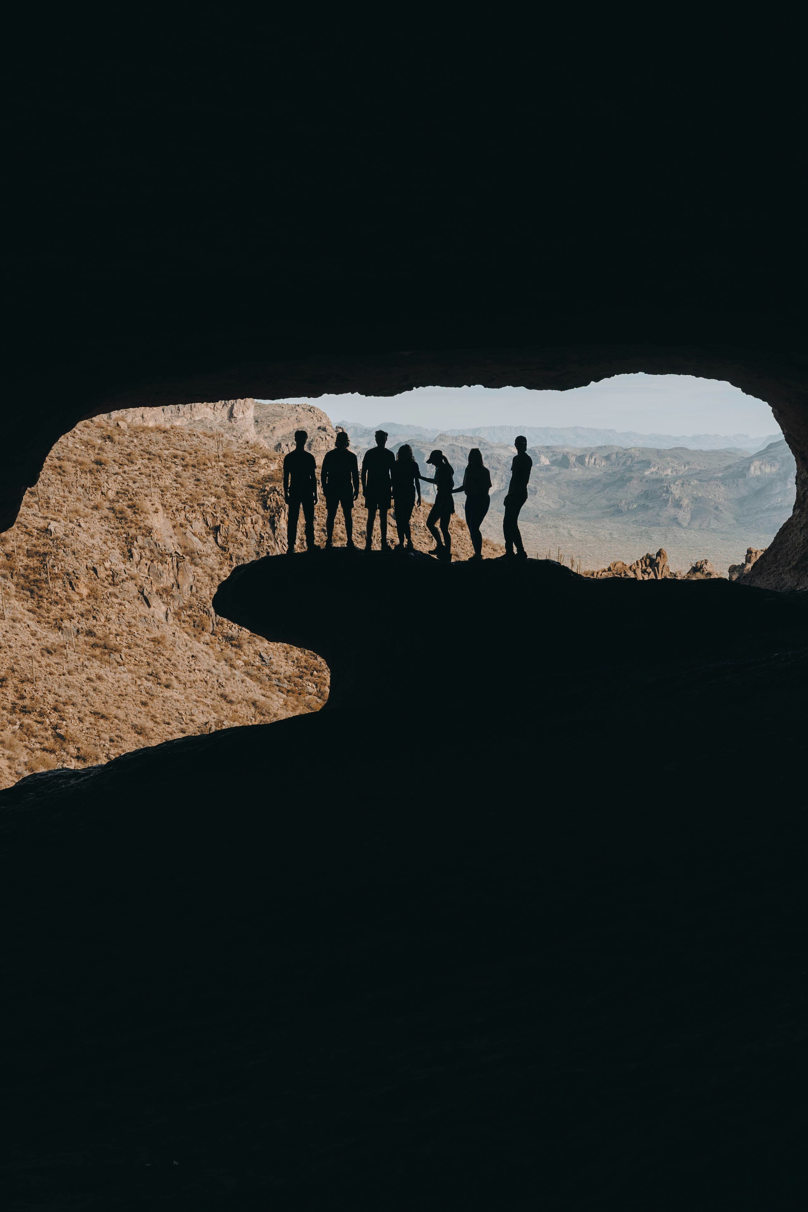 group of people in a cave looking to the outside